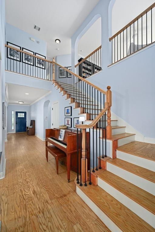 7721 Journeyville Dr, Austin, TX 78735 - stairway featuring arched walkways, a towering ceiling, wood finished floors, and baseboards