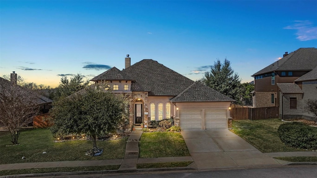 french country inspired facade with driveway, a chimney, fence, a garage, and a yard