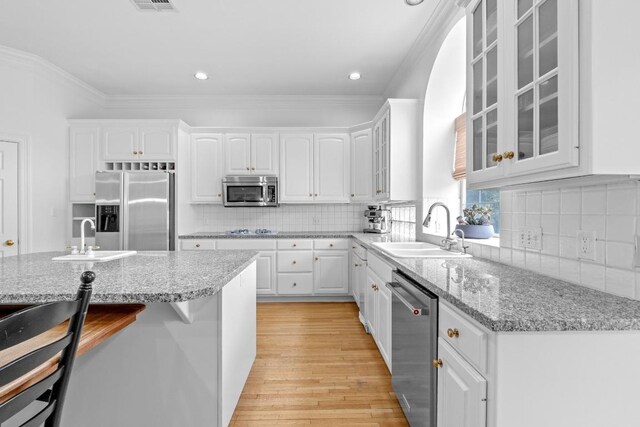5305 Cuesta Verde, Austin, TX 78746 - kitchen featuring appliances with stainless steel finishes, light wood-style flooring, white cabinetry, ornamental molding, and glass insert cabinets