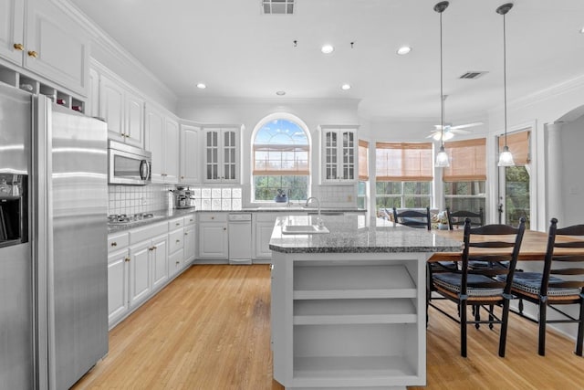 5305 Cuesta Verde, Austin, TX 78746 - kitchen featuring appliances with stainless steel finishes, open shelves, ornamental molding, light wood-type flooring, and a kitchen island with sink