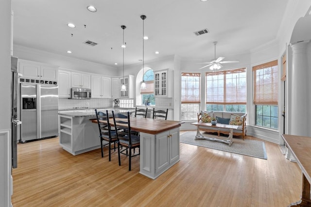 5305 Cuesta Verde, Austin, TX 78746 - kitchen with appliances with stainless steel finishes, a breakfast bar, a ceiling fan, light wood-style floors, and white cabinets