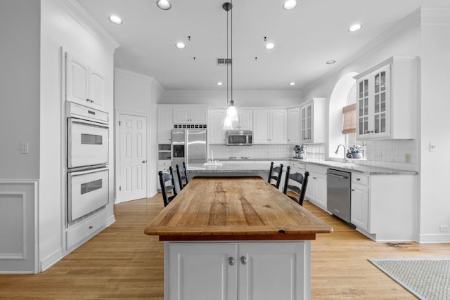 5305 Cuesta Verde, Austin, TX 78746 - kitchen with stainless steel appliances, a center island, white cabinets, crown molding, and tasteful backsplash