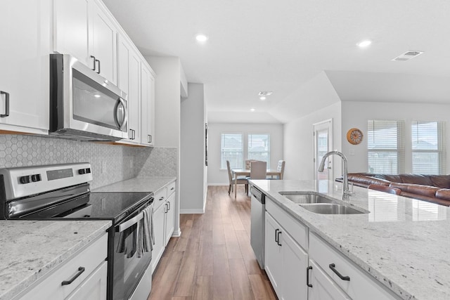 kitchen featuring visible vents, wood finished floors, stainless steel appliances, a sink, and backsplash