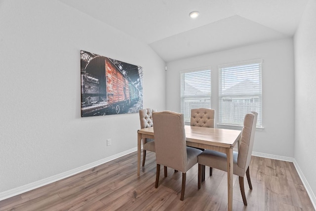 dining space with baseboards, wood finished floors, and vaulted ceiling
