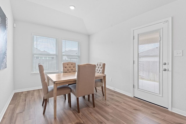 dining room with baseboards, lofted ceiling, and light wood-style floors