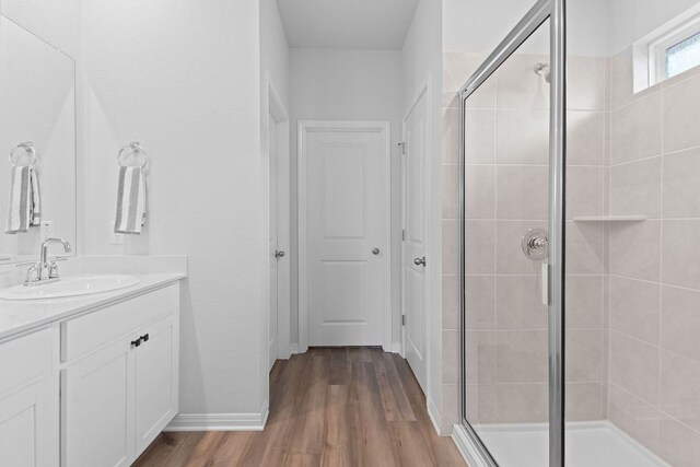 full bath with a stall shower, wood finished floors, and vanity