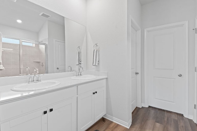 bathroom with visible vents, a sink, a shower stall, and wood finished floors