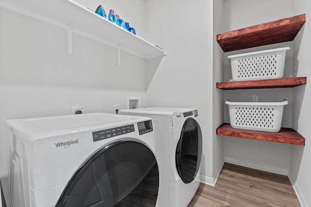 clothes washing area with washer and clothes dryer, baseboards, laundry area, and wood finished floors