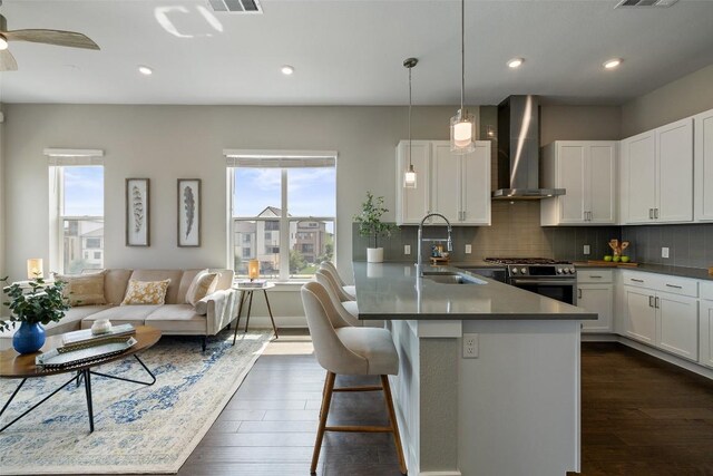 4501 Jackson Ave Unit 5205, Austin, TX 78731 - kitchen with stainless steel gas range, wall chimney range hood, tasteful backsplash, dark wood-type flooring, and recessed lighting