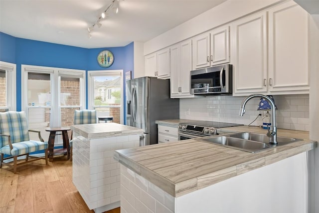 16 Tournament Way Unit 19, The Hills, TX 78738 - kitchen featuring stainless steel appliances, light wood-type flooring, track lighting, tasteful backsplash, and white cabinetry