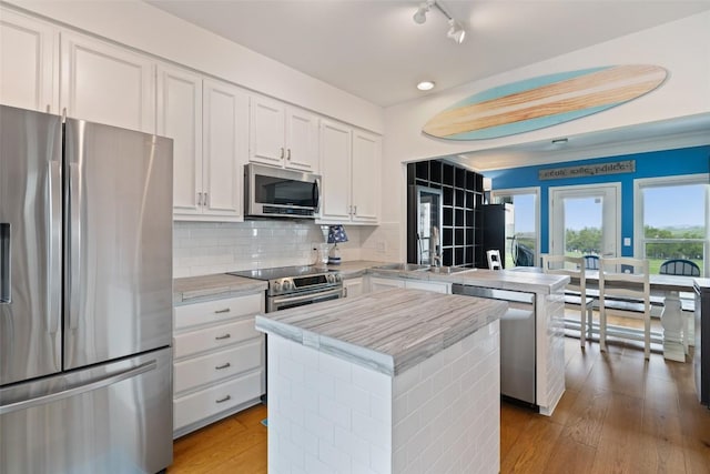 16 Tournament Way Unit 19, The Hills, TX 78738 - kitchen featuring stainless steel appliances, a peninsula, white cabinetry, a center island, and backsplash