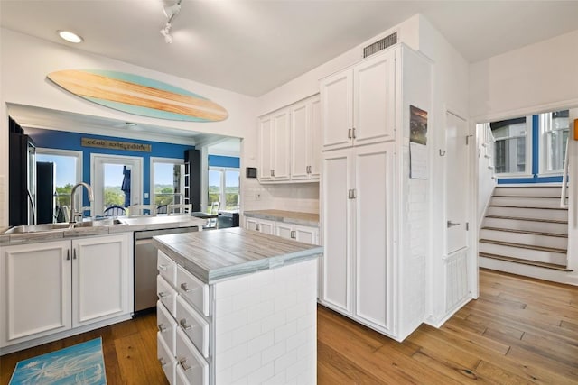 16 Tournament Way Unit 19, The Hills, TX 78738 - kitchen featuring dishwasher, white cabinetry, a kitchen island, light countertops, and wood finished floors