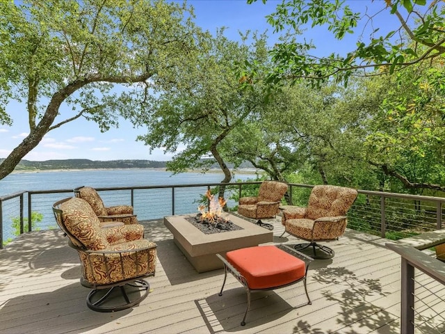 wooden terrace with an outdoor fire pit and a water view