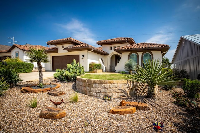 mediterranean / spanish home featuring a tiled roof, concrete driveway, stucco siding, and an attached garage