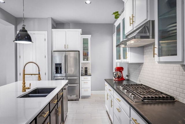 kitchen with a sink, pendant lighting, tasteful backsplash, under cabinet range hood, and stainless steel appliances