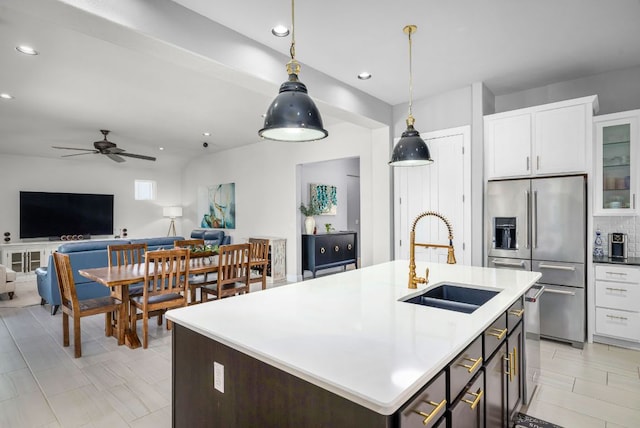kitchen featuring open floor plan, white cabinetry, stainless steel fridge, a sink, and pendant lighting