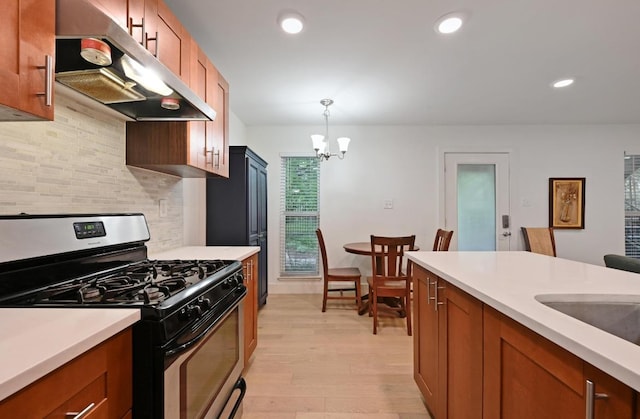 5820 Berkman Dr Unit 119, Austin, TX 78723 - kitchen featuring gas range, under cabinet range hood, decorative backsplash, light countertops, and light wood-style flooring