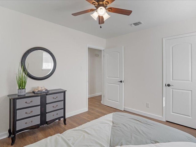 bedroom featuring wood finished floors, visible vents, baseboards, and ceiling fan