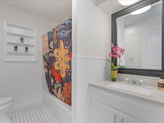 bathroom featuring a wainscoted wall, vanity, a decorative wall, and toilet