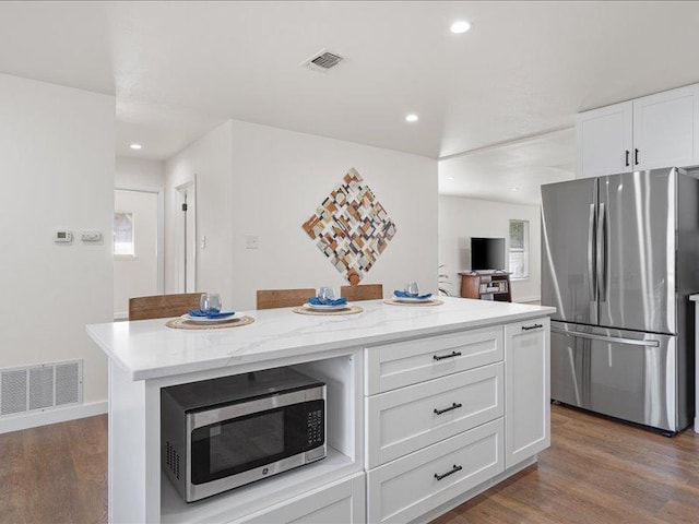 kitchen featuring white cabinetry, appliances with stainless steel finishes, wood finished floors, and visible vents