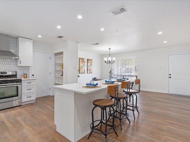 kitchen with recessed lighting, wood finished floors, visible vents, gas stove, and a kitchen bar