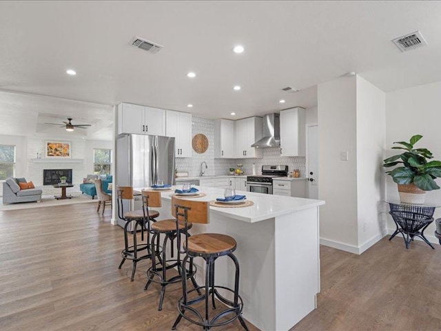 kitchen featuring wall chimney exhaust hood, appliances with stainless steel finishes, a sink, and visible vents
