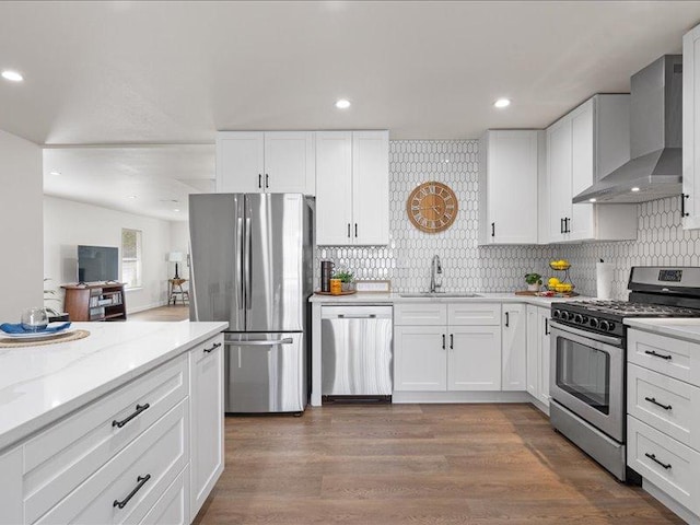 kitchen featuring wall chimney range hood, stainless steel appliances, and white cabinets