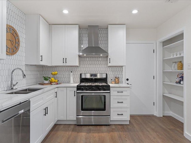 kitchen featuring a sink, stainless steel appliances, wall chimney exhaust hood, white cabinetry, and dark wood-style floors