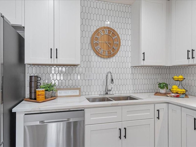 kitchen featuring white cabinets, stainless steel appliances, decorative backsplash, and a sink