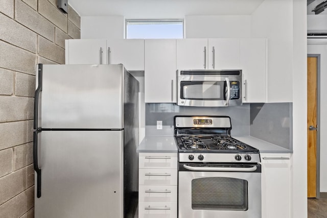 4801 S Congress Ave Unit H2, Austin, TX 78745 - kitchen with appliances with stainless steel finishes, white cabinets, light countertops, and concrete block wall