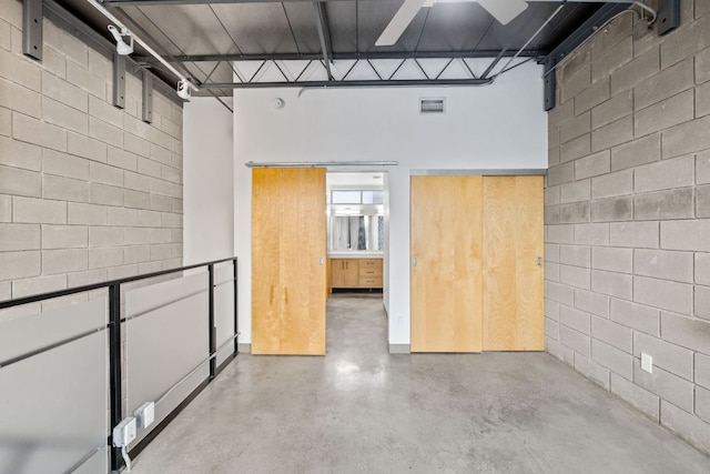 4801 S Congress Ave Unit H2, Austin, TX 78745 - unfurnished room with finished concrete floors, concrete block wall, and a towering ceiling