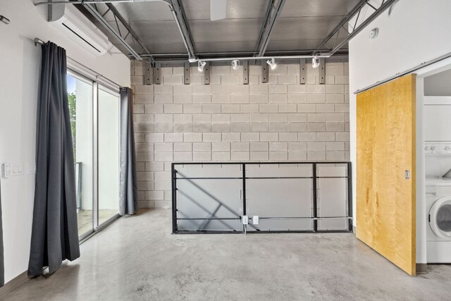 4801 S Congress Ave Unit H2, Austin, TX 78745 - basement with stacked washer and clothes dryer, concrete block wall, and a wall mounted AC