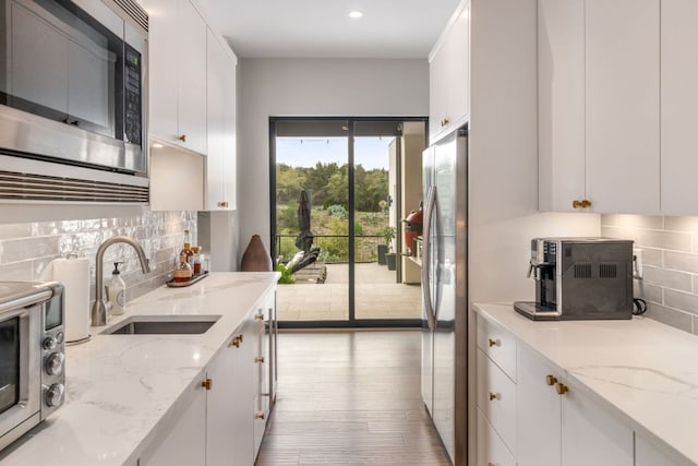 3931 R O Dr, Spicewood, TX 78669 - kitchen with stainless steel appliances, a sink, decorative backsplash, white cabinetry, and wood finished floors