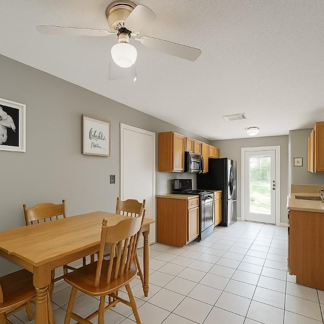 407 Trumpet Vine Trl, Cedar Park, TX 78613 - kitchen featuring stainless steel appliances, light countertops, light tile patterned floors, brown cabinets, and a ceiling fan