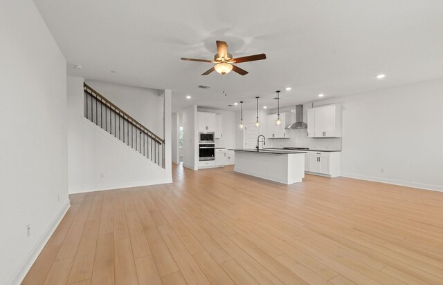 16824 Santiaguillo Trce, Manor, TX 78653 - unfurnished living room featuring ceiling fan, recessed lighting, light wood finished floors, and stairway