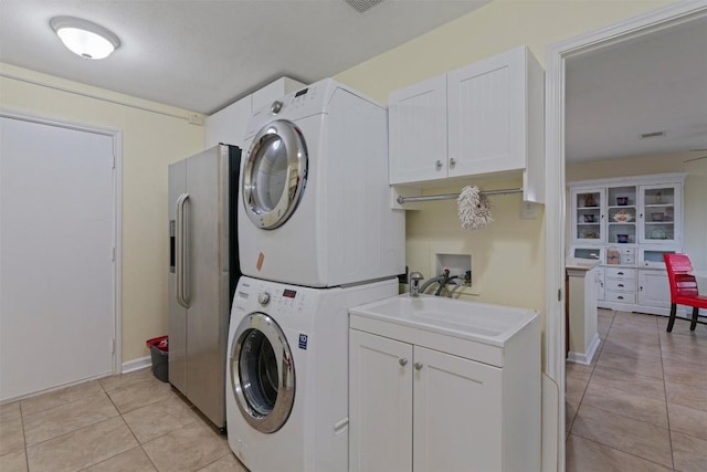 4932 Woodstock Dr, Georgetown, TX 78633 - laundry area with estacked washer and dryer, cabinet space, and light tile patterned flooring