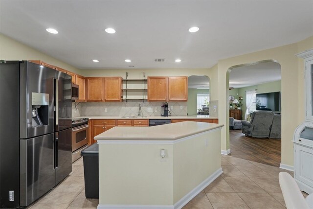 4932 Woodstock Dr, Georgetown, TX 78633 - kitchen with stainless steel appliances, arched walkways, a sink, light tile patterned floors, and light countertops