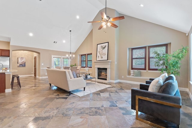 3985 Sapphire Loop, Round Rock, TX 78681 - living room featuring arched walkways, ceiling fan with notable chandelier, baseboards, and a glass covered fireplace