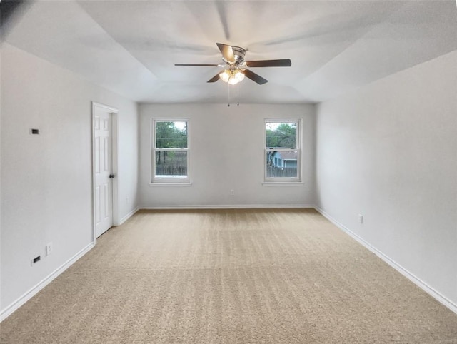spare room featuring light colored carpet, ceiling fan, and baseboards