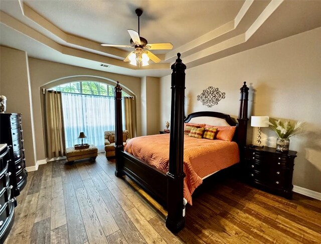 30105 Meadow Greens Dr, Georgetown, TX 78628 - bedroom with a tray ceiling, hardwood / wood-style flooring, and a ceiling fan