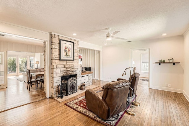 811 E 45th St, Austin, TX 78751 - living room with a textured ceiling, light wood-type flooring, ceiling fan, a stone fireplace, and recessed lighting