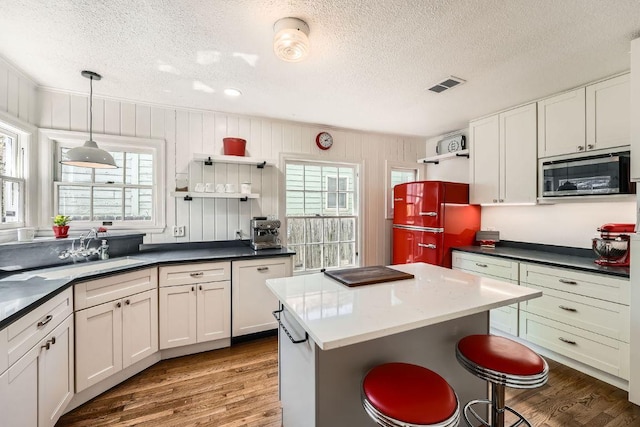 811 E 45th St, Austin, TX 78751 - kitchen with open shelves, stainless steel microwave, a textured ceiling, a sink, and healthy amount of natural light