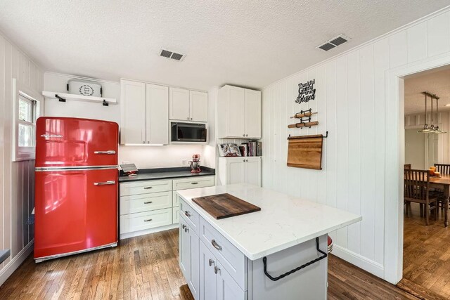 811 E 45th St, Austin, TX 78751 - kitchen featuring freestanding refrigerator, dark wood-style floors, stainless steel microwave, a textured ceiling, and a kitchen island