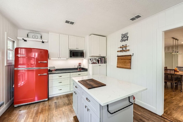 811 E 45th St, Austin, TX 78751 - kitchen featuring fridge, stainless steel microwave, dark wood-style flooring, a textured ceiling, and a center island