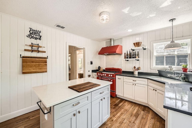 811 E 45th St, Austin, TX 78751 - kitchen featuring high end stainless steel range oven, wall chimney range hood, wood finished floors, a sink, and decorative light fixtures