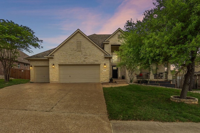 traditional home with a yard, an attached garage, driveway, and stone siding