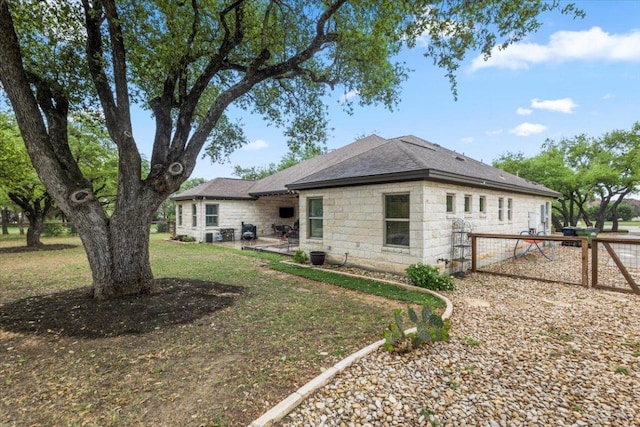 909 Highland Spring Ln, Georgetown, TX 78633 - rear view of house featuring stone siding, a patio area, roof with shingles, and a lawn