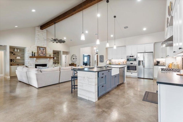 909 Highland Spring Ln, Georgetown, TX 78633 - kitchen with stainless steel appliances, a sink, dark countertops, white cabinetry, and a fireplace