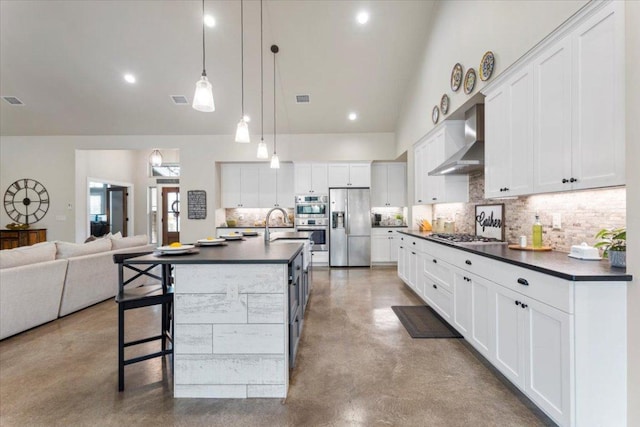 909 Highland Spring Ln, Georgetown, TX 78633 - kitchen with wall chimney exhaust hood, appliances with stainless steel finishes, dark countertops, finished concrete flooring, and high vaulted ceiling