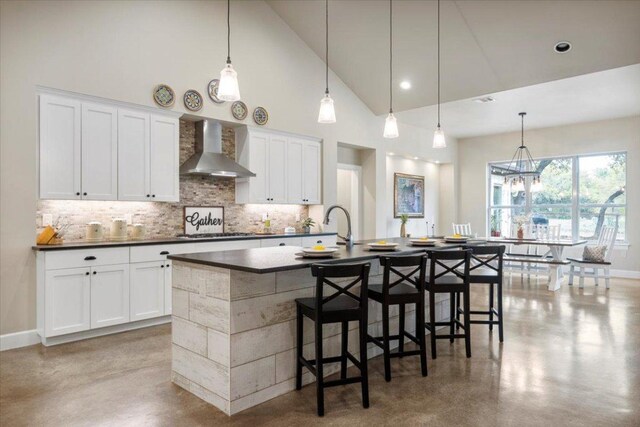 909 Highland Spring Ln, Georgetown, TX 78633 - kitchen featuring wall chimney range hood, dark countertops, tasteful backsplash, an island with sink, and concrete floors